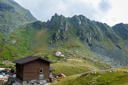 Mountain chalet in the foreground with mountain and sheep eating grass near mountain rescue house in...
