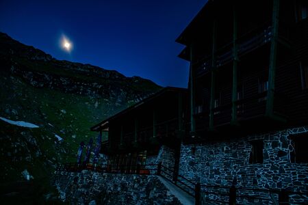 Moon lighting the night sky over a mountain cabinの写真素材