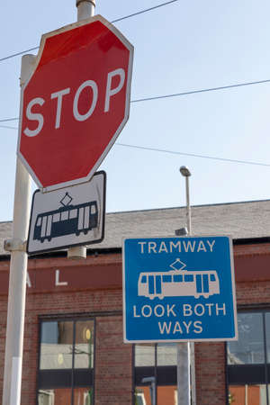Tramway sign saying stop and look both ways, with picture of tram, overhead tramslines in background