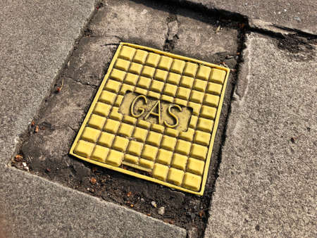 Rectangular yellow access cover for gas lines in a pavementの素材