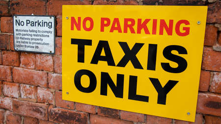 Two signs mounted on a brick wall indicating parking restrictions at Preston railway station June 2018の写真素材