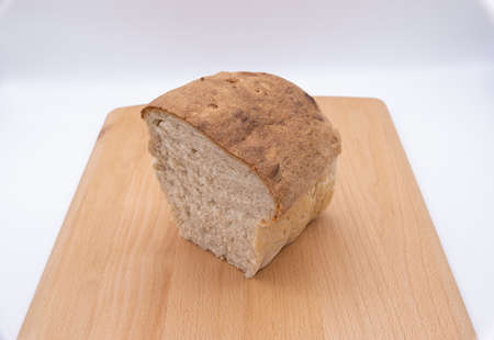 A plain white loaf cut in half on a bread board isolated against a white background showing the...