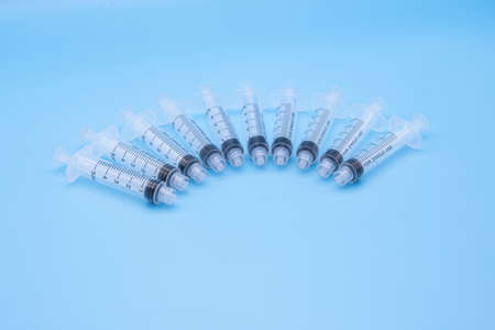 multiple clear plastic 5ml syringes isolated against a light blue backgroundの写真素材