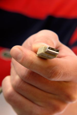 young man holds  computer cable USB plug ,  close up in  hand
