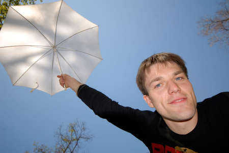 young guy with  white umbrella above  head on  background of  dark blue skyの写真素材