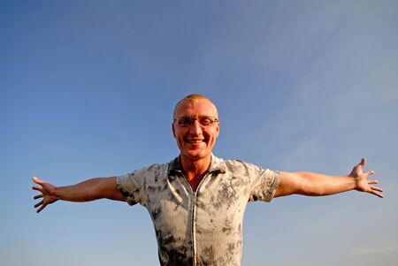 businessman has joyfully dissolved hands on  background of  dark blue skyの写真素材