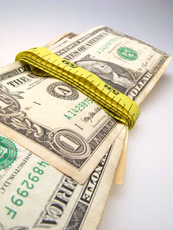 US dollar banknotes wrapped into measurement ruler on light backgroundの写真素材