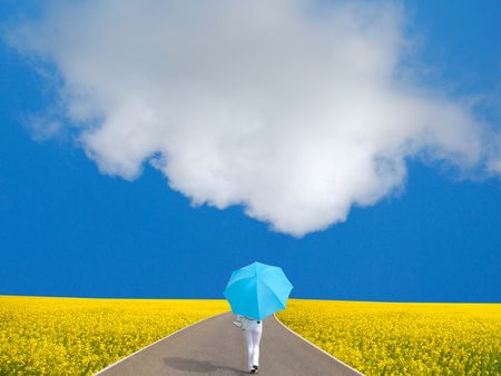 woman with umbrella in hands on background of field and skyの写真素材