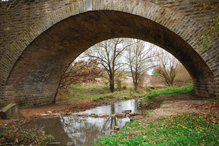 old stone bridge through small river, autumn