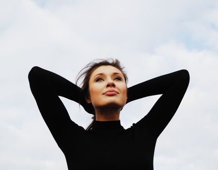 young nice woman with  lifted hands on  background of  blue sky