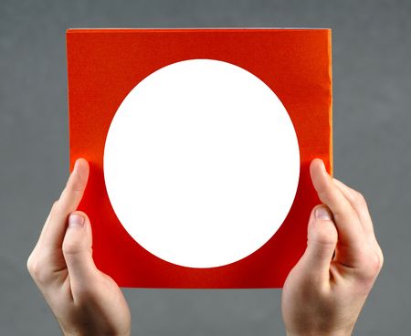 In hands  book of orange color with white circle in the center on  grey backgroundの写真素材