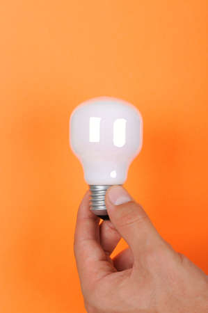 hand of businessman with an electric lamp, close up  on orange backgroundの写真素材