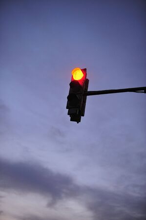Red signal of a traffic light on a background of the evening sky