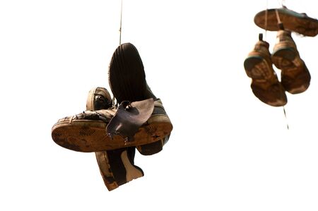old, torn  up sporting trainers  entangled by a lace on a light backgroundの写真素材