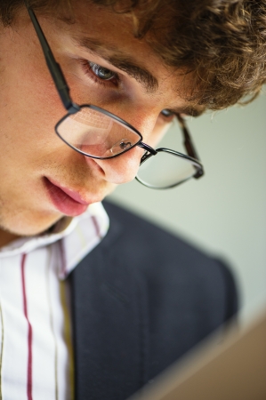 young vigorous businessman works wearing spectacles behind the laptopの写真素材
