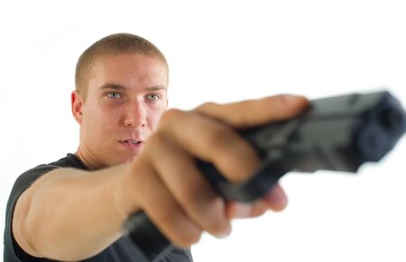 young man with the gun in a hand aims aside on a light background