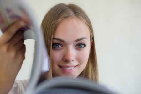  beautiful girl looks the magazine on a light backgroundの写真素材