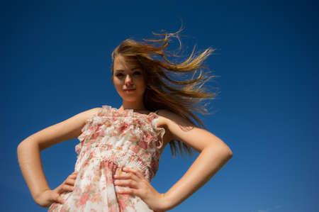 portrait of the smiling girl with a flowing hair against the blue sky