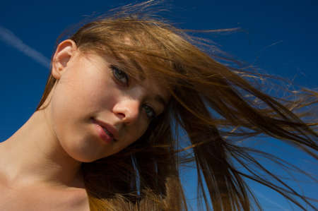 portrait of the girl with a flowing hair against the blue skyの写真素材