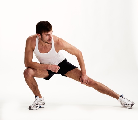young man the athlete does gymnastics on a light backgroundの写真素材