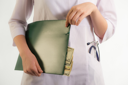 Doctor holding a folder with documents which show the moneyの写真素材