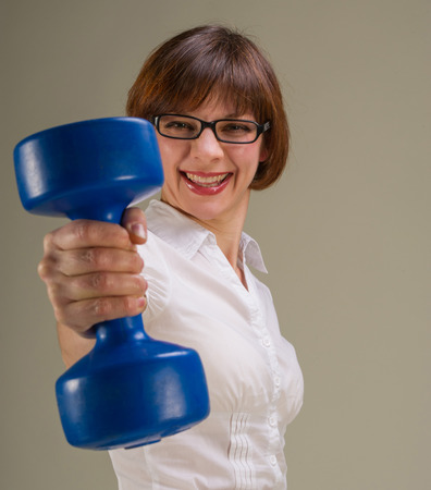 Attractive female businesswoman with dumbbells in hand  Woman wearing glasses and smiling の写真素材