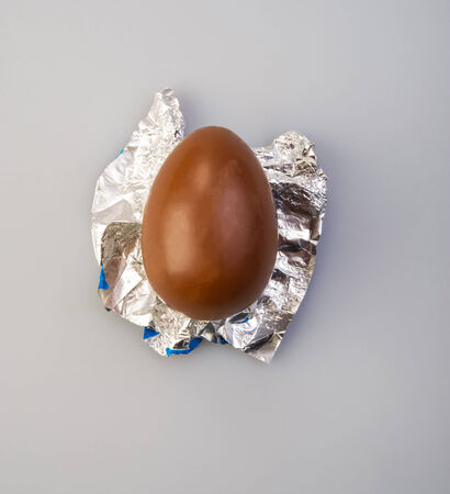 one chocolate egg lying on food foil on a light backgroundの写真素材