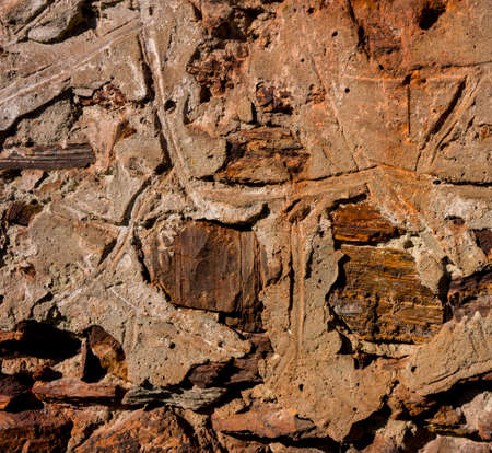 surface of the wall plastered with stones, illuminated by sunlight