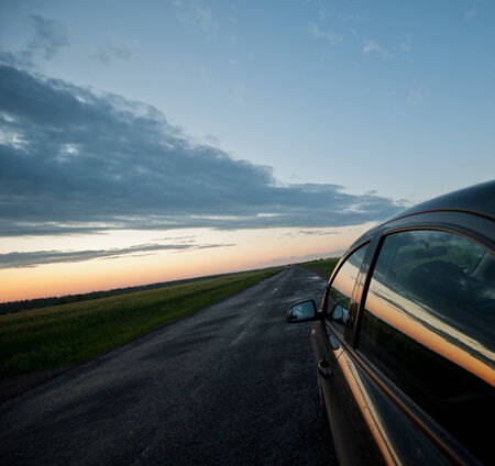 reflected in the glass of the car on the road against the evening skyの写真素材