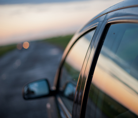 reflected in the glass of the car on the road against the evening skyの写真素材