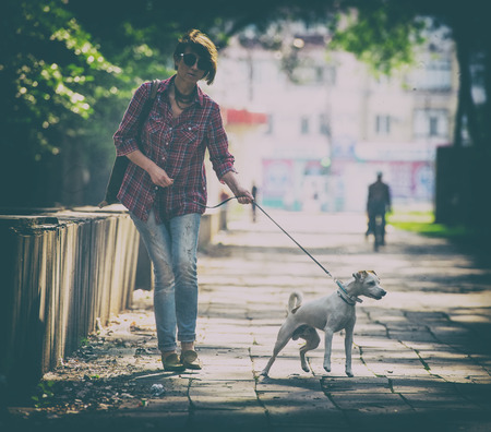 woman walking with a pet in the city parkの写真素材