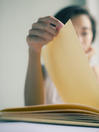 Portrait of an attractive young brunette asian woman flipping albumの写真素材