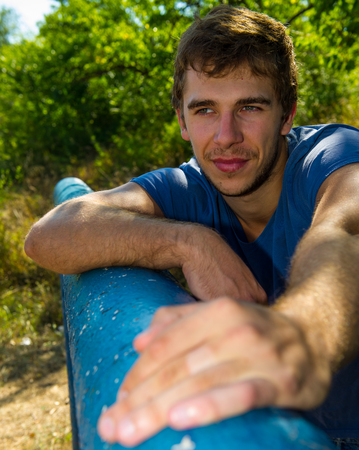 portrait of a cute guy on a background of green plantsの写真素材