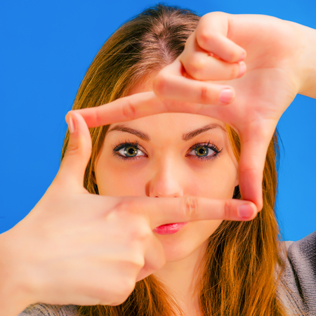 young beautiful girl looks crossed fingers frameの写真素材