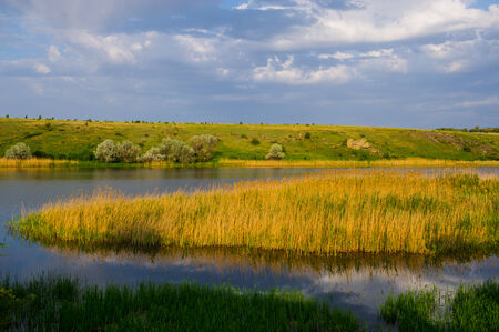 spring rural landscape, river field and cloudsの写真素材