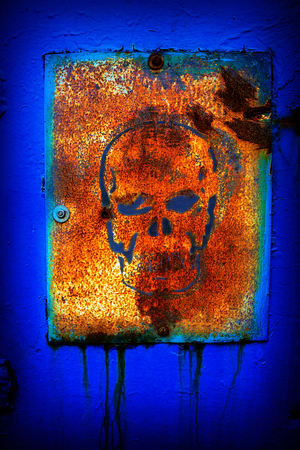 old rusty metal sign with a skull painted on the wallの写真素材