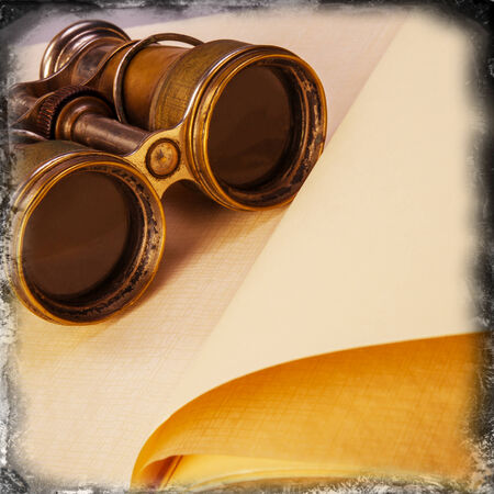 old binoculars on an open bookの写真素材