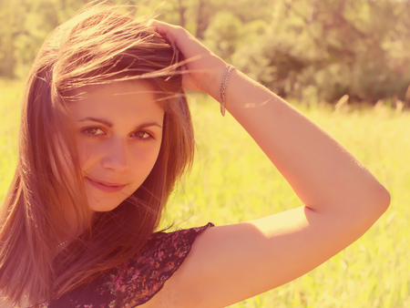 portrait of a girl with a bent arm which looks with interest on nature backgroundの写真素材