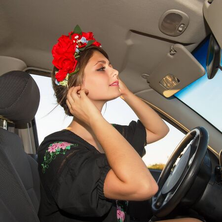 woman drives a car and corrects wreath