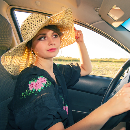 woman drives a car and adjusts his hat