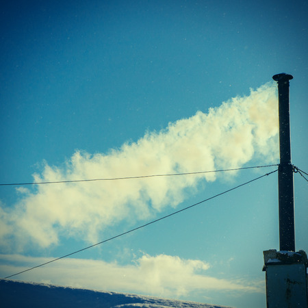 smoke from the flue pipe on the background of the sky on a winter dayの写真素材