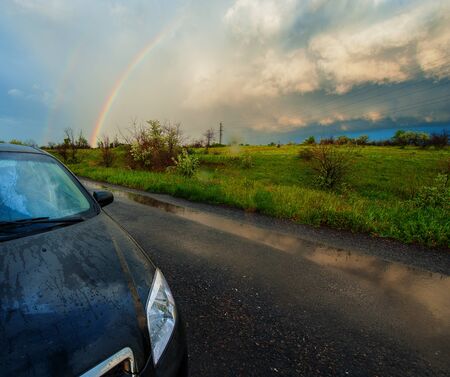 car on a background of the rainbow and rain cloudsの写真素材
