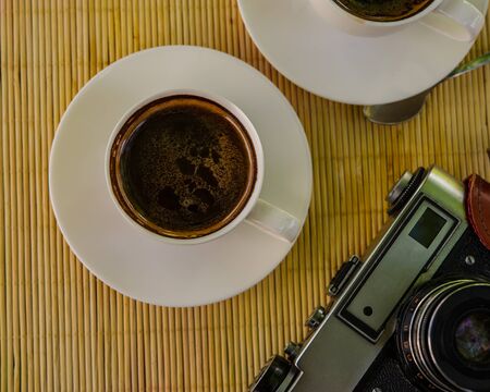 two cups of coffee and an old film camera