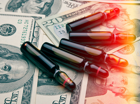 vials with a medical drug on a background of dollar bills