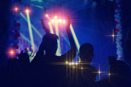 silhouettes of concert crowd in front of bright stage lights