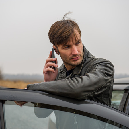 Businessman with a phone in his hand says standing near a carの写真素材