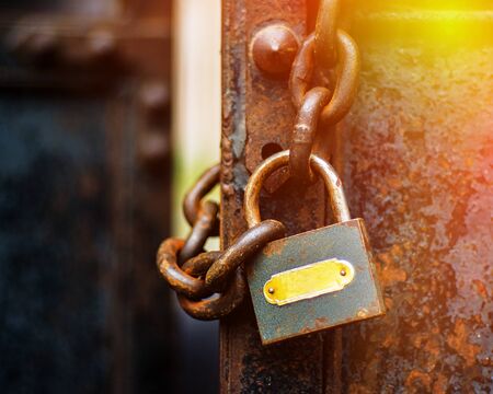 old padlock hanging on a rusty chain and a metal gate
