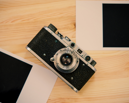 Old film camera and photo on the surface of a wooden table