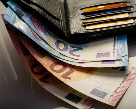 paper euro notes in a wallet and credit cards. Paper denominations of ten and twenty euros.