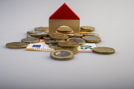 pile of euro coins and paper bills and a house layout on a light background. Business and finance. Business metaphor.の写真素材